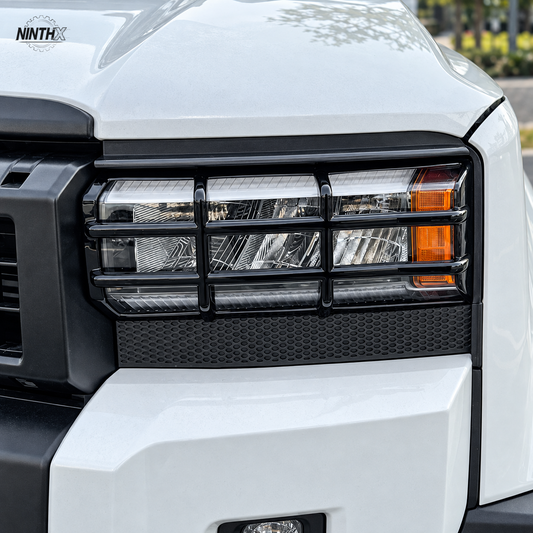 Gloss black headlight guard installed on the front lamp of a white Toyota Land Cruiser Prado LC250.