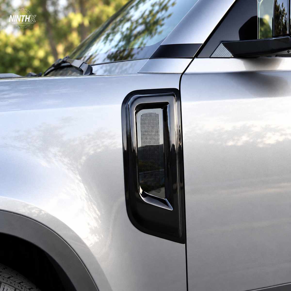 Gloss black fender air intake bug screen cover fitted to the side vent of a Defender L663.