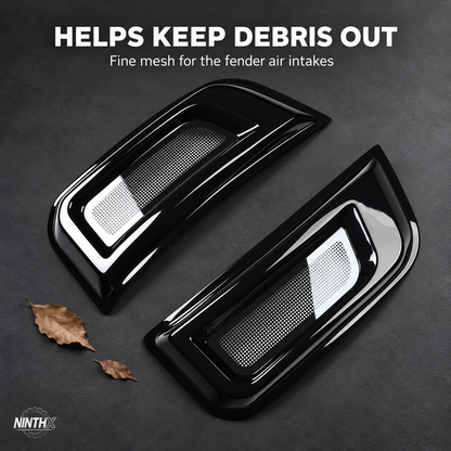 Defender L663 fender air intake bug screen covers with fine mesh, displayed beside dry leaves on a dark background.